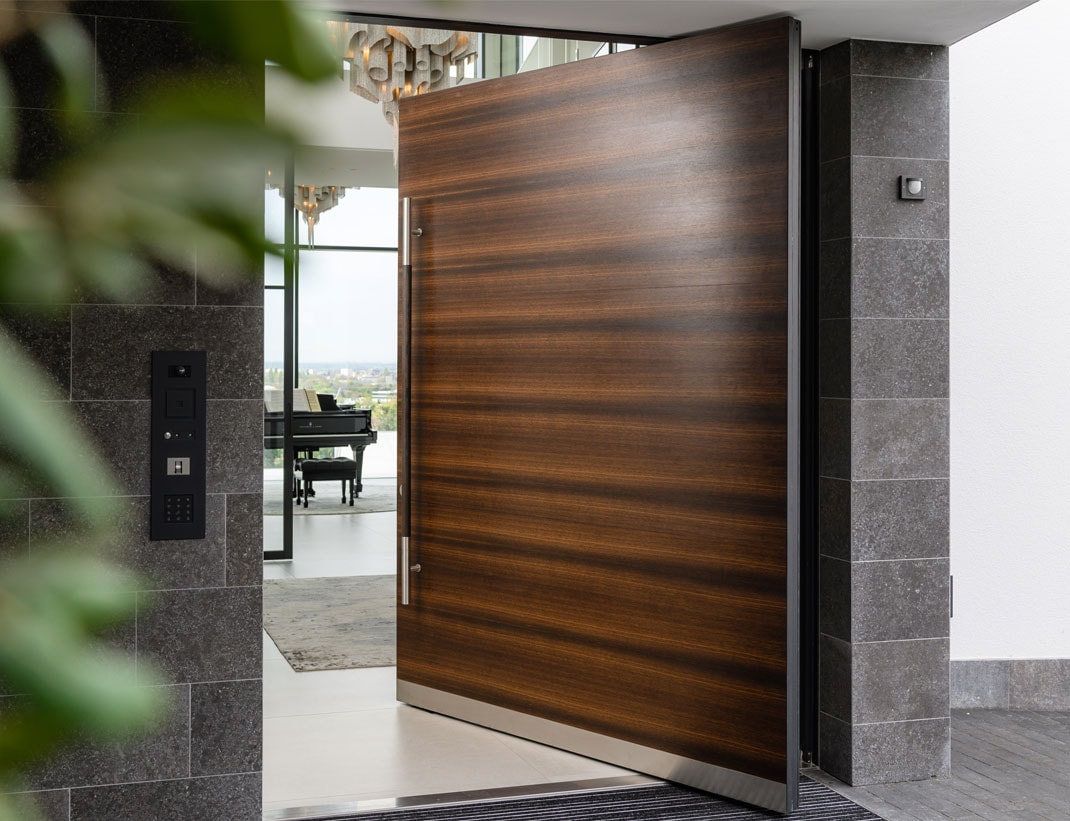Oversized wood pivot exterior door — luxury entrance